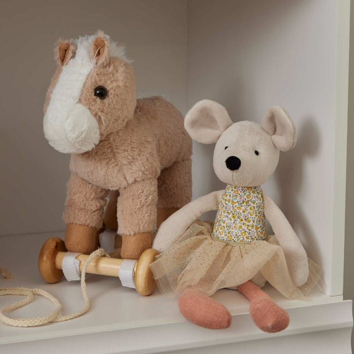 A child pulling a plush horse on wooden wheels
